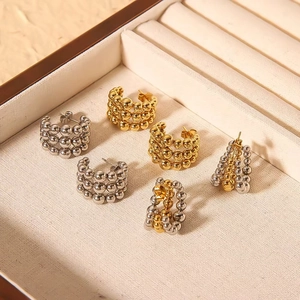 Three pairs of C-shaped beaded earrings in gold and silver finish on a beige jewelry box