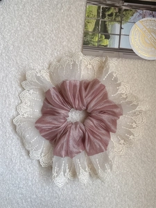 Detail of elegant pink scrunchie with white lace embroidery on soft plush background