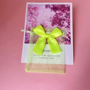 Detail of light green organza gift bag with yellow satin bow and elegant black text