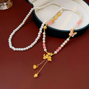 Detail of lotus flower and pink butterfly pendant on a pearl necklace in a jewelry box