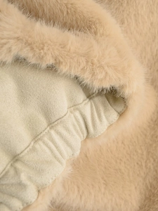 Détail de la bordure en fausse fourrure et texture tricotée sur le gilet beige chic