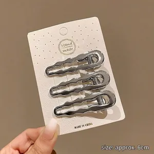 Gros plan de trois épingles à cheveux ondulées en argent métallique de 6 cm de long