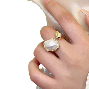 Vintage style gold-plated open ring with irregular pearl on a hand, white background