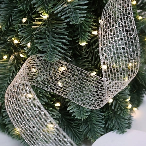 Silver mesh Christmas ribbon with warm LED lights wrapped around a festive tree