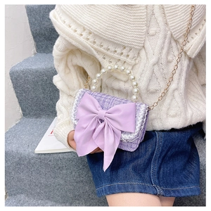 Detail of purple tweed girls' crossbody bag with pearl handle and lace bow accent
