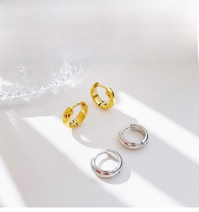 Close-up of minimalist chunky hoop earrings in polished gold and silver finishes