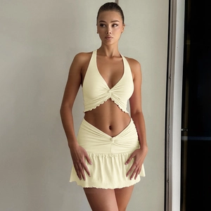 Close-up of pale yellow two-piece set featuring a halter crop top and ruched mini skirt