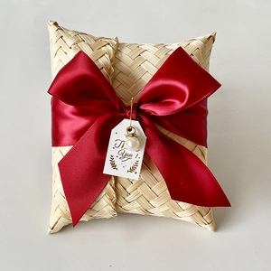 Detail view of handmade woven bamboo gift box with red satin ribbon and pearl charm decoration