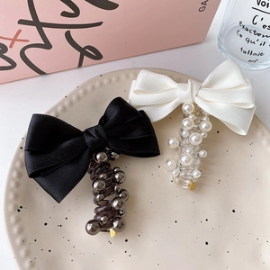 Detail of silk bow and pearl telephone wire hair ties in a decorative ceramic plate