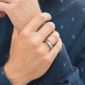 Close-up of a silver-gray hammered texture stainless steel ring on a finger