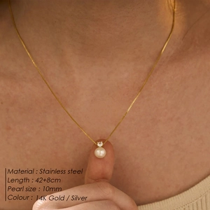 Detail of 10mm pearl pendant on a stainless steel 14K gold chain worn by a model