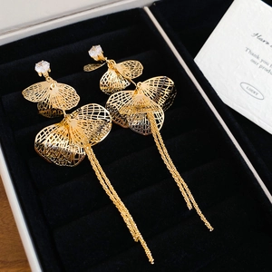 Détail de boucles d'oreilles feuilles de ginkgo dorées avec zircons et glands sur velours