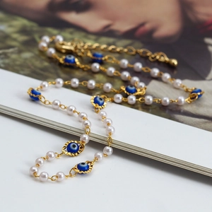 Beaded Evil Eye necklace with white pearls and gold chain on a fashion magazine
