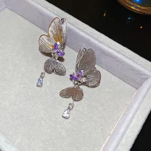 Silver butterfly tassel earrings with purple zircons and teardrop pendants in a box