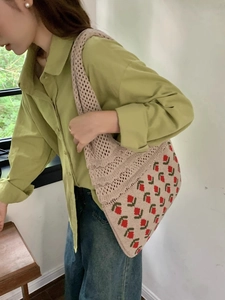 Detail of knitted tote bag featuring red tulip pattern with a model in green shirt