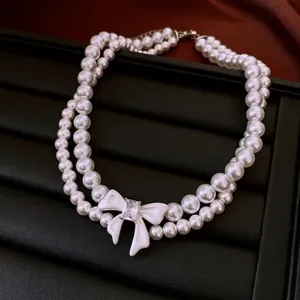 Double-layered pearl necklace with a white bow pendant and sparkling zircon stone