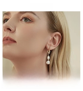 Close-up of French vintage knotted gold earrings with baroque freshwater pearls on a model