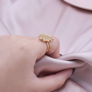 Golden double-band ring with beaded round plate detail on pink satin background