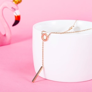 Rose gold LOVE Y-necklace with ring and bar pendant draped over a white ceramic cup