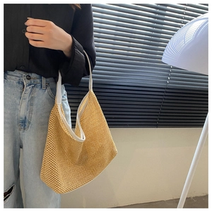 Detail of yellow hollow mesh woven tote bag with white shoulder strap on a female model