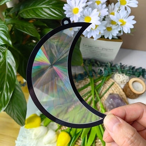 Handheld moon-shaped suncatcher showing vibrant rainbow refraction and black frame