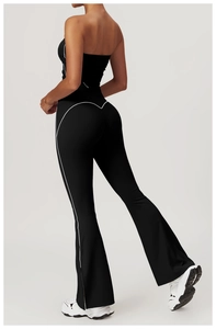 Detail of high-waisted yoga pants with white heart stitching and flared legs in black
