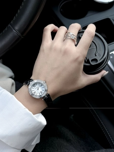 Detailed close-up of a luxury women's watch with diamond bezel and black leather strap