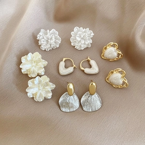Macro view of five pairs of pearl and floral earrings on champagne silk fabric