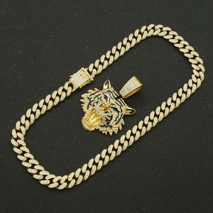 Detailed view of gold plated cuban chain with iced out tiger head pendant on black background