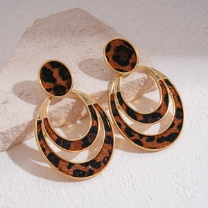 Detail of vintage leopard print earrings with gold-tone edges on a stone surface