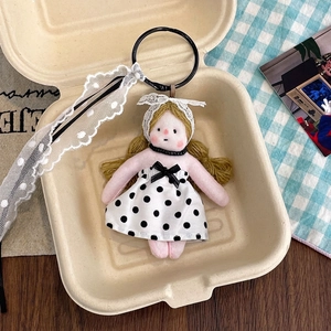 Detailed view of floral doll keychain with lace ribbon in a decorative gift box