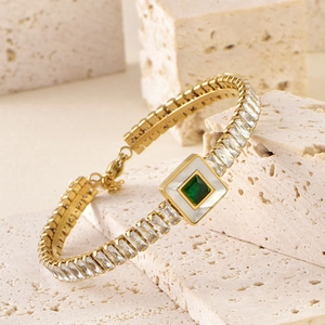 Detailed shot of golden chain bracelet with green gemstone and square diamond accents