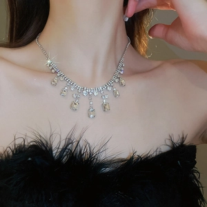 Close-up of a silver-tone necklace featuring square-cut rhinestones and teardrop pendants