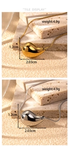 Detailed macro view of gold and silver teardrop pendants on minimalist stone base
