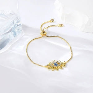 Detailed macro view of gold-plated evil eye slider bracelet with blue center gemstone