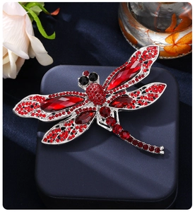 Macro shot of dragonfly brooch with red rhinestones and silver alloy base on jewelry box