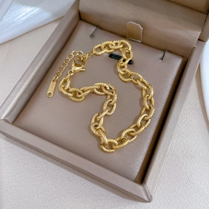 Detailed shot of gold chain bracelet with textured links and clasp in a jewelry box