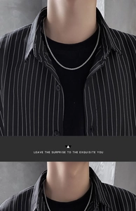 Silver keel chain necklace on male model wearing black striped shirt for casual style