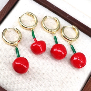 Detailed macro view of cute red cherry drop earrings with green stems in a jewelry box