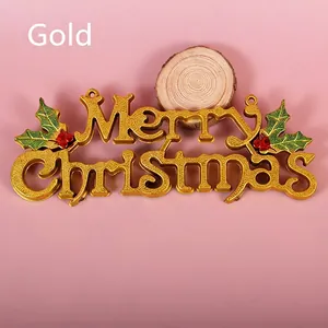 Golden Merry Christmas sign with holly berries for holiday door decoration on pink backdrop