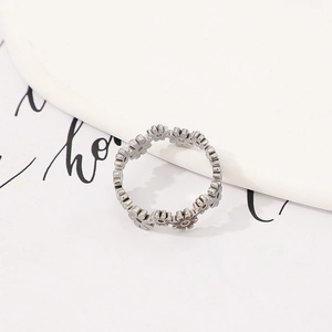 Detail of silver daisy flower ring with hollow cutout design on decorative background
