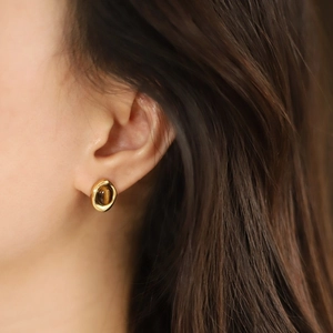 Close-up of golden tiger eye stud earrings on a model showing vintage circular design