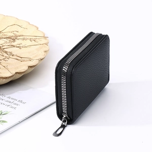 Close-up of black leather card holder showing textured litchi grain and silver zipper