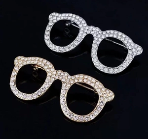 Close-up of gold and silver cat-eye glasses brooches with sparkling crystal rhinestones