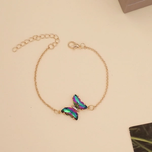 Macro detail of a butterfly pendant with iridescent wings and tiny crystals on a gold chain