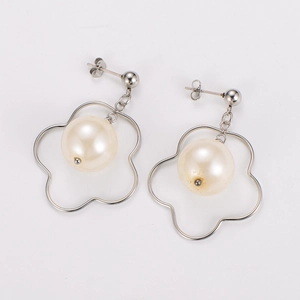 Close-up of silver hollow flower earrings with elegant white pearl bead pendants