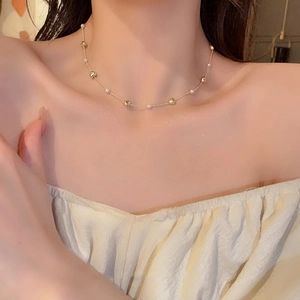 Close-up of golden heart and pearl necklace on female collarbone for a delicate look