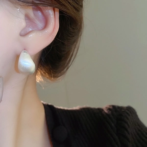 Detail of pearlescent water drop earring with gold plating on a female model