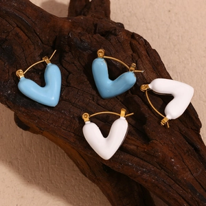 Detailed macro of hollow heart-shaped gold-plated earrings with blue and white enamel