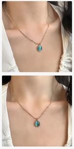 Detailed view of an oval blue cat-eye stone pendant on a gold beaded necklace